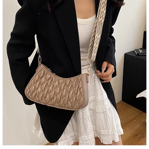 Détail du sac demi-lune matelassé kaki clair avec large bandoulière sur modèle