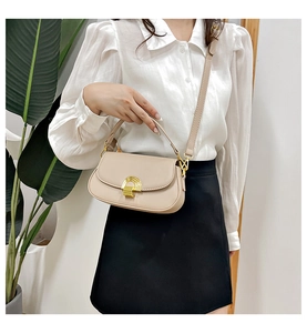 Détail d'un sac à bandoulière beige avec boucle métallique rotative semi-circulaire dorée