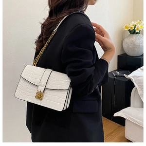 Detail of white crocodile pattern shoulder bag with a vintage gold flower-shaped lock