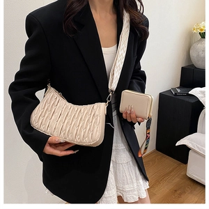 Sac hobo plissé beige chic avec sangle tissée et mini portefeuille sur mannequin en blazer