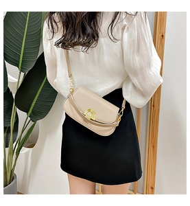 Détail d'un sac besace en cuir beige crème avec boucle dorée porté en bandoulière