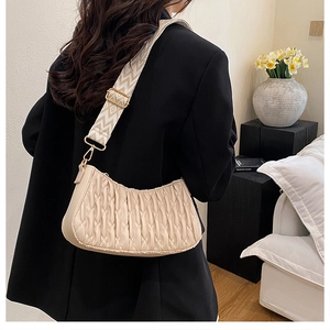 Gros plan du sac beige plissé avec une large bandoulière tissée aux motifs géométriques
