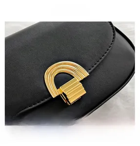 Vue macro détaillée du sac en cuir noir montrant le fermoir en métal doré et les surpiqûres