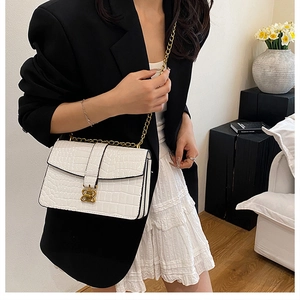 Close-up of elegant gold petal lock and crocodile embossed texture on a white bag