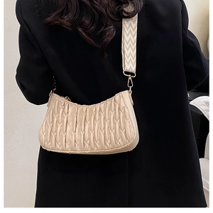 Détail du sac beige plissé avec large bandoulière géométrique et finitions dorées chic