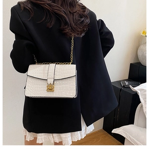 White croc-effect crossbody bag with gold chain strap shown on a black blazer