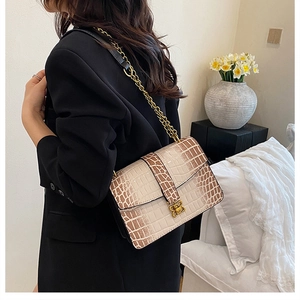 Detail of elegant beige crocodile pattern chain bag with golden butterfly clasp