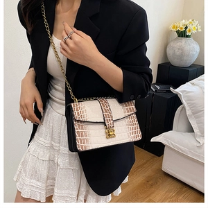 Detailed view of crocodile pattern crossbody bag with golden clasp and chain strap