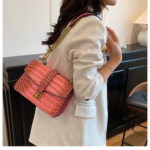 Pink crocodile-embossed chain bag with a vintage gold buckle shown in a lifestyle setting