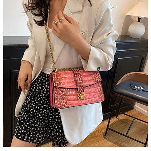 Detailed shot of pink crocodile pattern crossbody bag with golden B-shaped buckle and chain strap