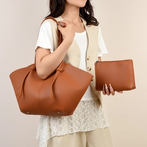 Caramel brown pebbled leather wing tote bag with matching pouch on beige background
