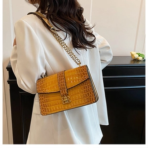 Close-up of yellow crocodile texture crossbody bag with gold butterfly clasp and chain