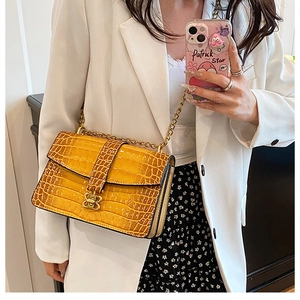 Detail of yellow crocodile pattern bag featuring a gold butterfly clasp and chain strap