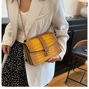 Detail of yellow crocodile pattern handbag with gold chain strap and B-shaped clasp