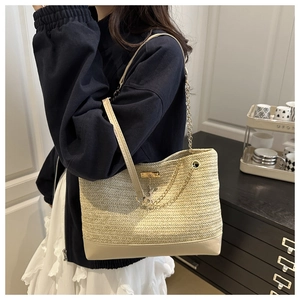 Detail of beige straw tote bag with chain straps and leather base for a summer look