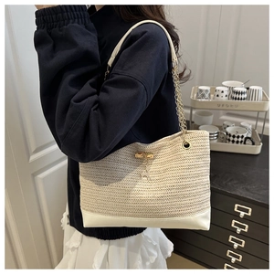 Detail of straw woven tote bag featuring gold chain strap and decorative deer pendant