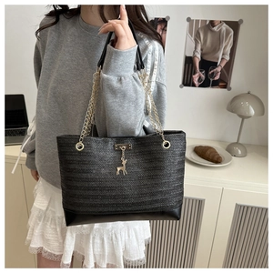 Détail d'un sac cabas en paille noire avec chaîne dorée et pendentif cerf élégant