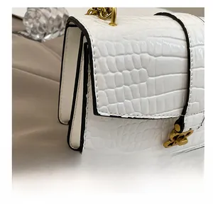 Detail showing high-quality stitching on white croc-effect crossbody bag with gold buckle
