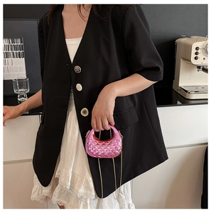 Detailansicht der gesteppten Mini-Handtasche in Pink mit Goldkette getragen von Model