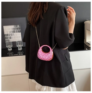 Nahaufnahme einer rosa gesteppten Mini-Tasche mit Goldkette an der Schulter des Models