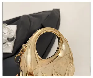 Detail der goldenen Acryl-Clutch mit rundem Griff und gesteppter Textur