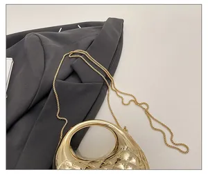 Detail der goldenen Acryl-Handtasche mit Rautenmuster und feinem Metallkettenriemen