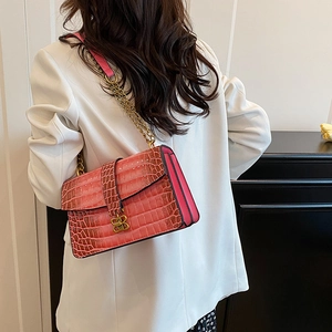 Pink croc-effect chain shoulder bag with gold hardware worn by a model in a white suit