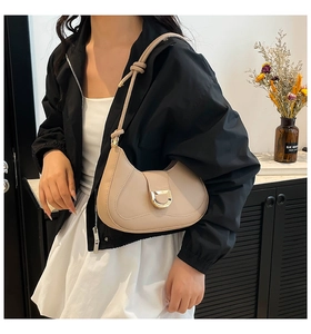 Détail du sac demi-lune beige avec boucle dorée en D et bandoulière à nœud élégante