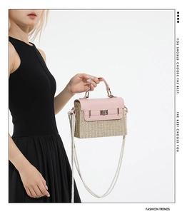 Sac boîte en paille rose tendance avec fermoir métallique porté sur une robe noire