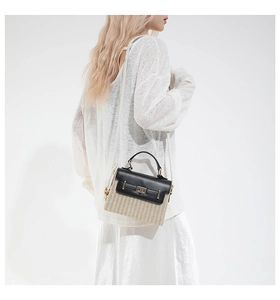 Sac bandoulière en paille et cuir noir porté par un mannequin avec une sangle tressée