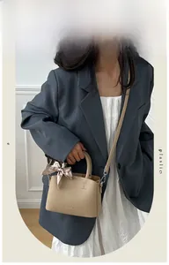 Close-up of beige lychee leather handbag featuring decorative silk scarf and fashion text