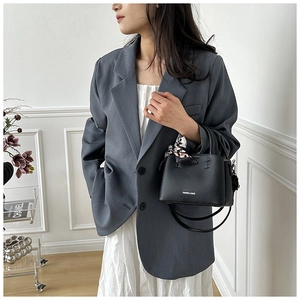 Detail of black textured leather bucket bag with printed silk scarf and fashion lettering