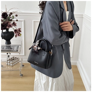 Close-up of black litchi grain leather bucket bag with silk scarf and silver logo detail
