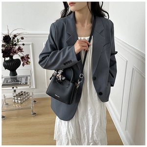 Detailed shot of black lychee leather mini bucket bag with silk scarf on top handle
