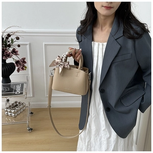 Detail of beige lychee grain leather bucket bag with silk scarf handle and long strap