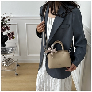 Detail of soft leather bucket bag with silk scarf handle and adjustable shoulder strap