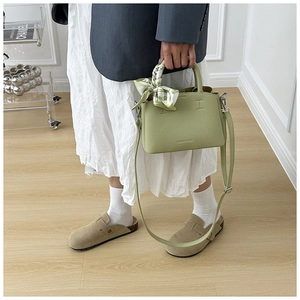 Detail of light green pebbled leather bucket bag with printed silk scarf and silver hooks