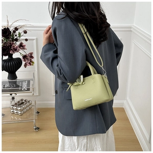 Green textured leather bucket bag with silk scarf and detachable strap on model