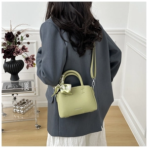 Detail view of sage green pebbled leather bucket bag with printed silk scarf handle
