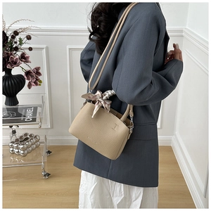 Detailed close-up of beige lychee grain leather bucket bag with a silk scarf handle