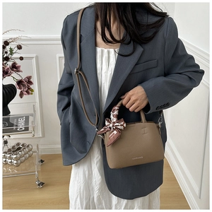 Detail of brown litchi pattern leather bucket bag with silk scarf and fashion text