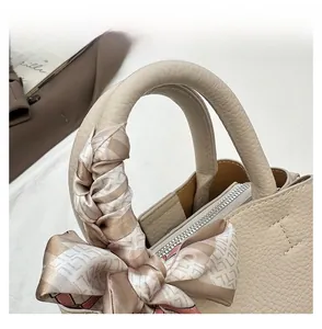 Detail of silk scarf wrapped handle on a beige pebbled leather bucket handbag