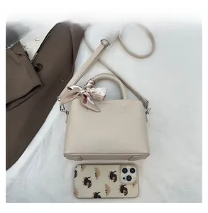 Top view of beige leather bucket bag with silk scarf and smartphone for scale