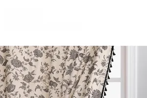 Detail of vintage beige curtain with black floral print and spherical fringe edge