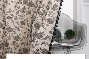 Detailed close-up of bohemian linen curtain with black floral print and tassel trim