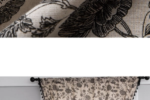 Detail of bohemian cotton linen curtain fabric with black floral print and tassel trim