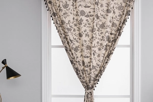 Detail of bohemian cotton linen curtain with black floral toile print and tassel edges
