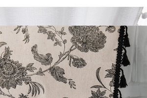 Detailed view of bohemian cotton linen fabric with floral print and black tassel fringe