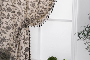 Detail of vintage floral pattern on beige fabric with black tassel fringe trim