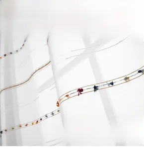 Detail of white semi-transparent sheer curtain with colorful tassels and geometric texture